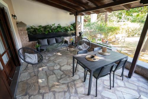 a patio with a table and chairs and a couch at Το Σπίτι της Γιαγιάς in Paralia Rachon