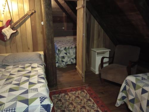 a bedroom with a guitar and a bed and a chair at Casa de toras in Campo Alegre