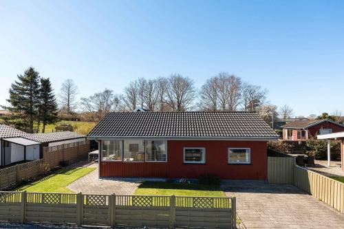 a red house with a fence in front of it at Cozy Cottage With A View Of Kerteminde Fjord in Munkebo