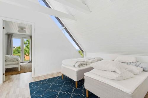 a white bedroom with two beds and a blue rug at Lovely Holiday Flat Close To The Beach in Sandvig