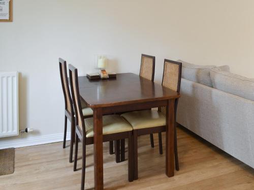 a dining room table with chairs and a couch at Teal Cottage in Embleton