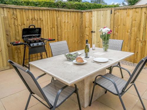 a table with four chairs and a grill in a backyard at Wits End Cottage in Martin
