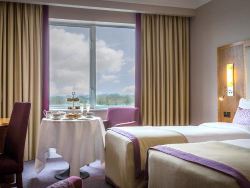 a hotel room with two beds and a table and a window at Charleville Park Hotel & Leisure Club IRELAND in Charleville