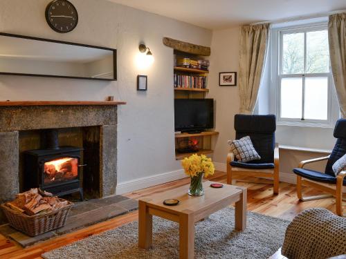 un soggiorno con camino e TV di Miller Cottage a Malham