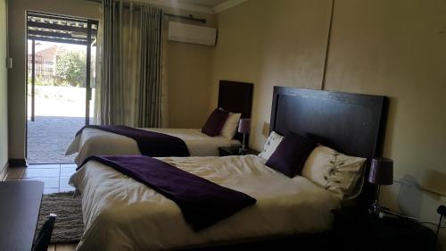 a hotel room with two beds and a balcony at Korundum Lodge in Vereeniging