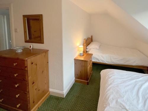 a bedroom with two beds and a dresser with a mirror at Caladh Beag in Lochranza