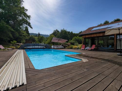 - une piscine sur une terrasse en bois à côté d'une maison dans l'établissement Chambre spacieuse avec piscine, spa et hammam - FR-1-589-721, à Anould