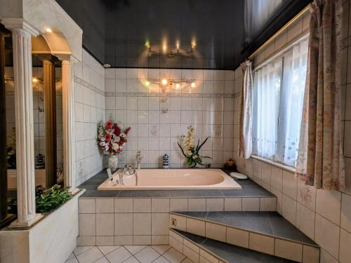 ein großes Badezimmer mit Badewanne und Fenster in der Unterkunft Chambre familiale avec piscine et SPA à Anould - FR-1-589-708 in Anould