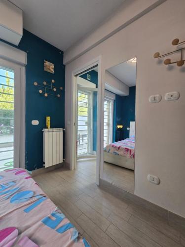 1 dormitorio con paredes azules, 1 cama y espejo en Welcome Love, en Acilia