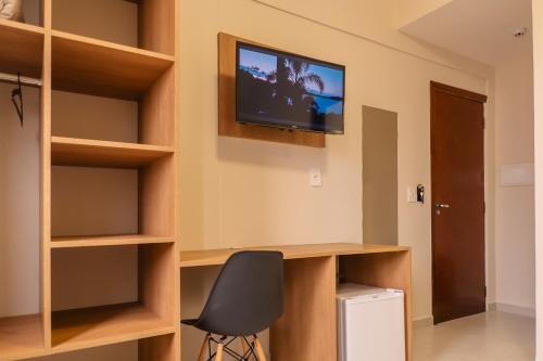 a room with a desk and a television on the wall at HANNA Amsterdam Hotel & Eventos in Florianópolis