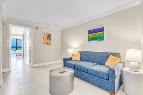 Una sala de estar con un sofá azul y una mesa. en Paradis By Casanita - Oceanfront Lux Designer Suite, en Myrtle Beach