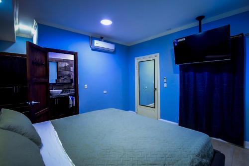 a blue bedroom with a bed and a television at Hotel Bugambilias in Estelí