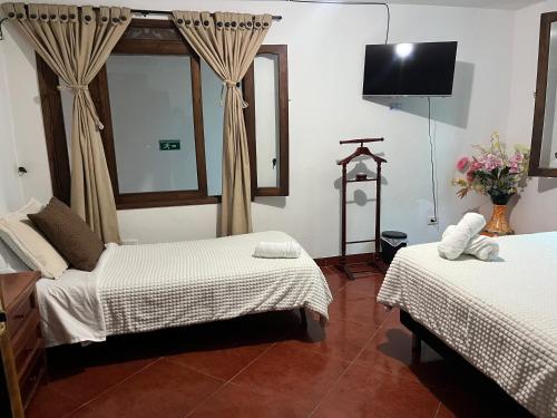 a bedroom with two beds and a tv on the wall at VILLA LEWANA 2 in Villa de Leyva