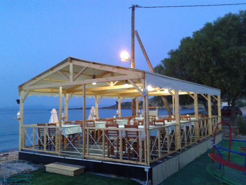 a pavilion with tables and chairs on the water at Aigeiros Apartments & restaurant in Skala Mistegnon