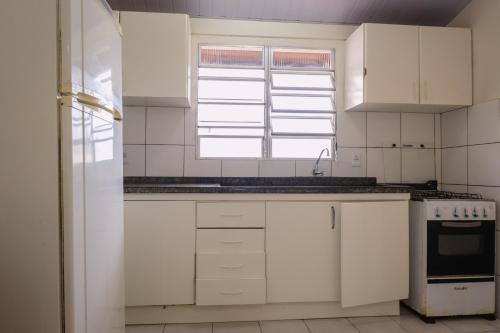 a kitchen with white cabinets and a window at HANNA Amsterdam Hotel & Eventos in Florianópolis