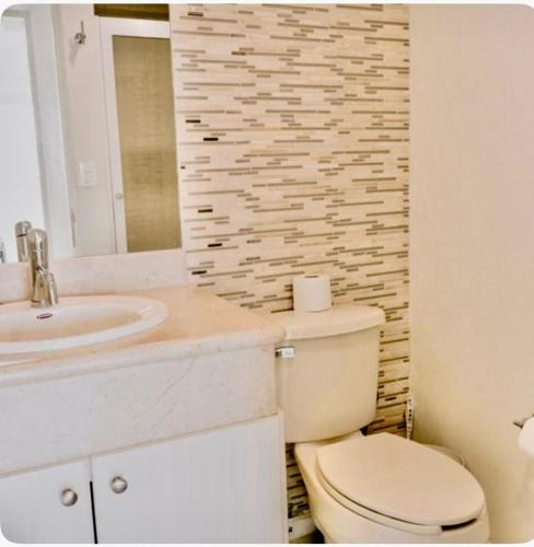 a bathroom with a toilet and a sink and a mirror at FRENTE AL MAR A PIE DE PLAYA ALBERCA y JACUZZI 7 in Mazatlán