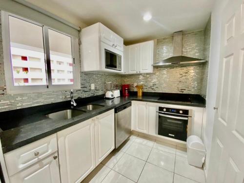 a kitchen with white cabinets and a sink at FRENTE AL MAR A PIE DE PLAYA ALBERCA y JACUZZI 7 in Mazatlán