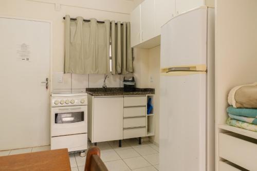a kitchen with white cabinets and a refrigerator at HANNA Amsterdam Hotel & Eventos in Florianópolis