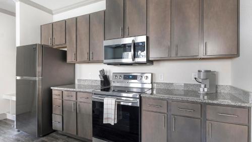 a kitchen with stainless steel appliances and wooden cabinets at Landing at The Flats at Shadowglen - Manor in Manor