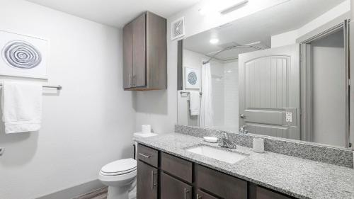 a bathroom with a sink and a toilet and a mirror at Landing at The Flats at Shadowglen - Manor in Manor