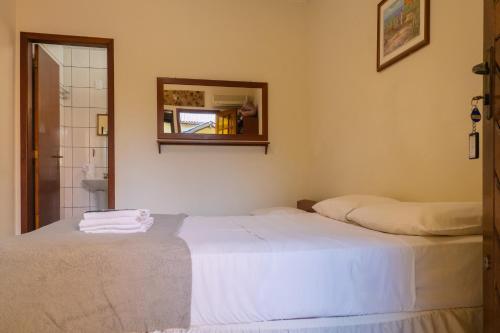 a bedroom with a white bed and a mirror at HANNA Amsterdam Hotel & Eventos in Florianópolis