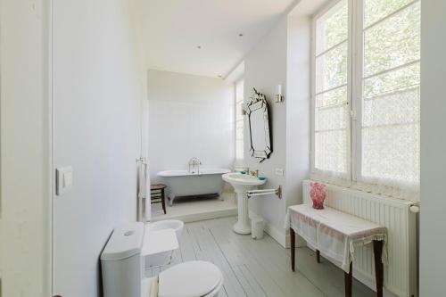 a white bathroom with a tub and a sink at Domaine de la Grotte in Sore