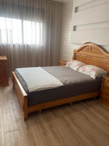 Un dormitorio con una cama grande con cabecero de madera. en Élégance et Confort à Proximité de la Plage, en Bouznika