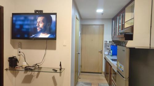 a television hanging on a wall in a kitchen at Low-key Suites Trees Residences in Manila