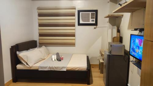 a small bedroom with a bed and a television at Low-key Suites Trees Residences in Manila