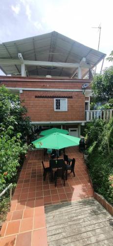 a table with a green umbrella in front of a building at La Morada Del Gavilucho in San Carlos