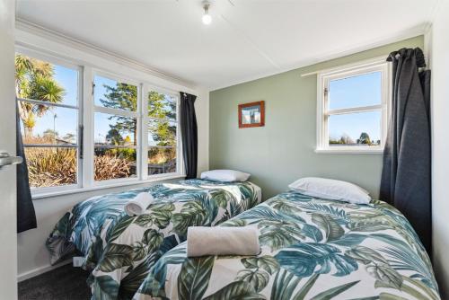zwei Betten in einem Zimmer mit zwei Fenstern in der Unterkunft The Flax Cottage - National Park Holiday Home in Raurimu Spiral