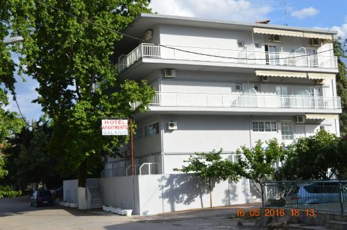 a white building with a sign in front of it at Galanis Studios and Apartments in Platamonas