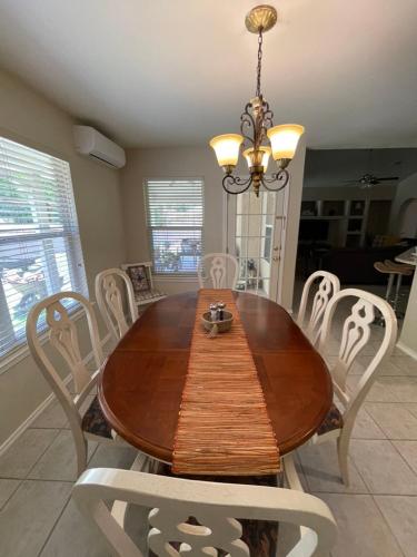 a dining room table with white chairs and a chandelier at Casa Escondida in San Antonio