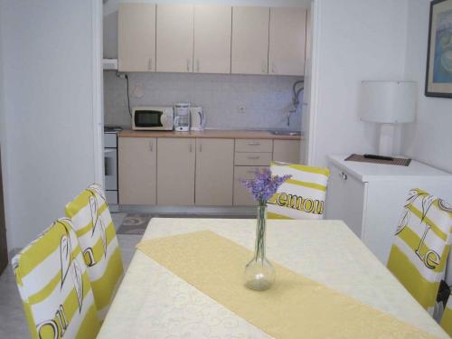 kuchnia ze stołem, na którym stoi wazon z kwiatami w obiekcie Apartment in Zadar - Zadar Riviera 7970 w mieście Zadar