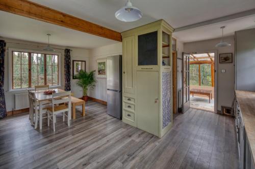 a kitchen and dining room with a table and a refrigerator at Tranquil Woodland Cottage, 10-Min Drive to Clifton in Pill