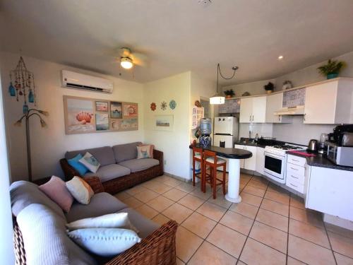 a living room with a couch and a kitchen at Depa con alberca, 10 min caminando playa Ixtapa in Ixtapa