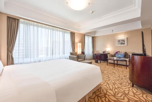 a hotel room with a large bed and a living room at Furama Hotel Dalian in Dalian