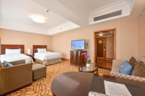 a hotel room with a bed and a living room at Furama Hotel Dalian in Dalian