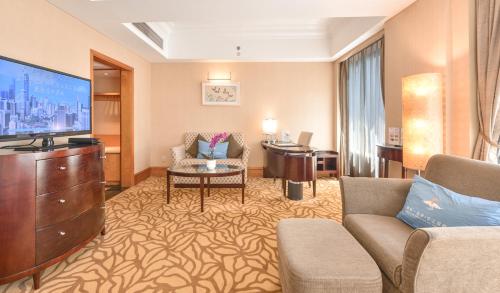 a living room with a couch and a desk and a television at Furama Hotel Dalian in Dalian