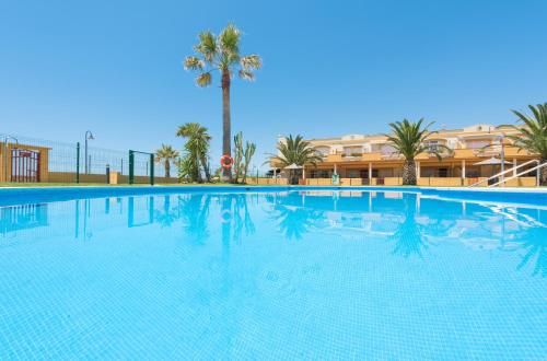 una gran piscina con palmeras y un edificio en Apartamento Tortuga I, en Tarifa
