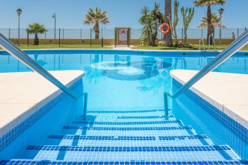 a swimming pool with palm trees and the ocean at Apartamento Tortuga I in Tarifa