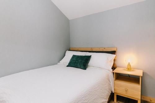 a small bedroom with a white bed and a night stand at Adventure Knap Shack in Nordegg