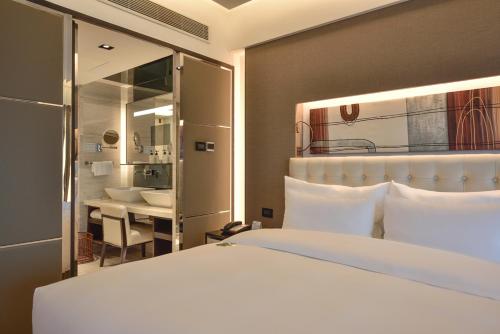 a bedroom with a large white bed and a bathroom at Furama Hotel Dalian in Dalian