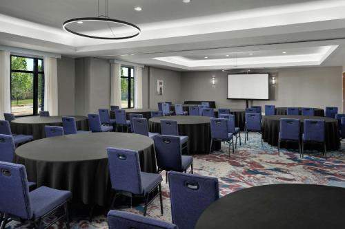 a conference room with tables and chairs and a screen at TownePlace Suites by Marriott Dallas DFW Airport North/Grapevine in Grapevine
