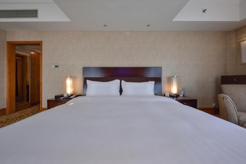 a large bed in a hotel room with two lamps at Furama Hotel Dalian in Dalian