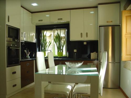a kitchen with a glass table and white chairs at Casa do Terreiro in Beiral do Lima