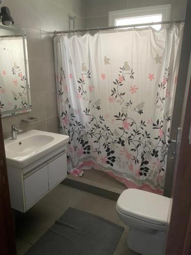 ein Badezimmer mit Duschvorhang, Toilette und Waschbecken in der Unterkunft Amwaj sidi abed el rahman in Banī Ghālib