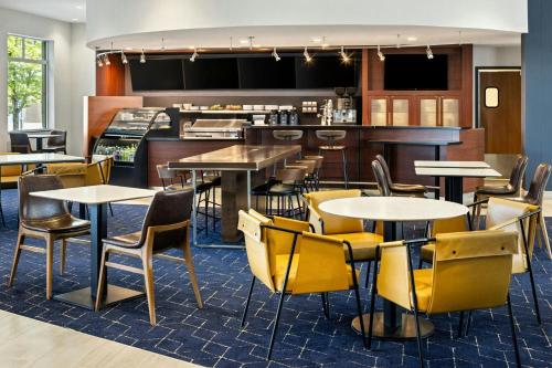 a restaurant with tables and chairs and a bar at Courtyard Minneapolis Maple Grove Arbor Lakes in Maple Grove