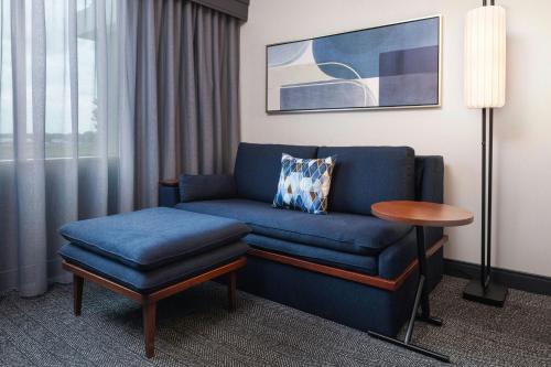 a living room with a blue couch and a table at Courtyard Minneapolis Maple Grove Arbor Lakes in Maple Grove