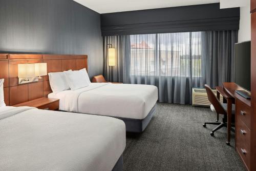 a hotel room with two beds and a desk at Courtyard Minneapolis Maple Grove Arbor Lakes in Maple Grove